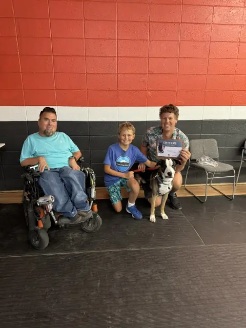 A Prodogz Basic Obedience graduate and young family member posing with Jason Lake, their black-and-white dog and class certificate — photo 2
