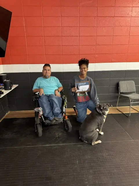 Jason Lake with a Basic Obedience graduate holding her certificate beside a large gray dog at Prodogz in Medford, Oregon — photo 3